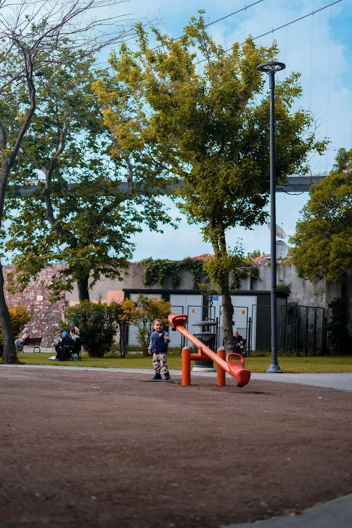 A child playing on a seesaw in a vibrant outdoor playground setting during the day.