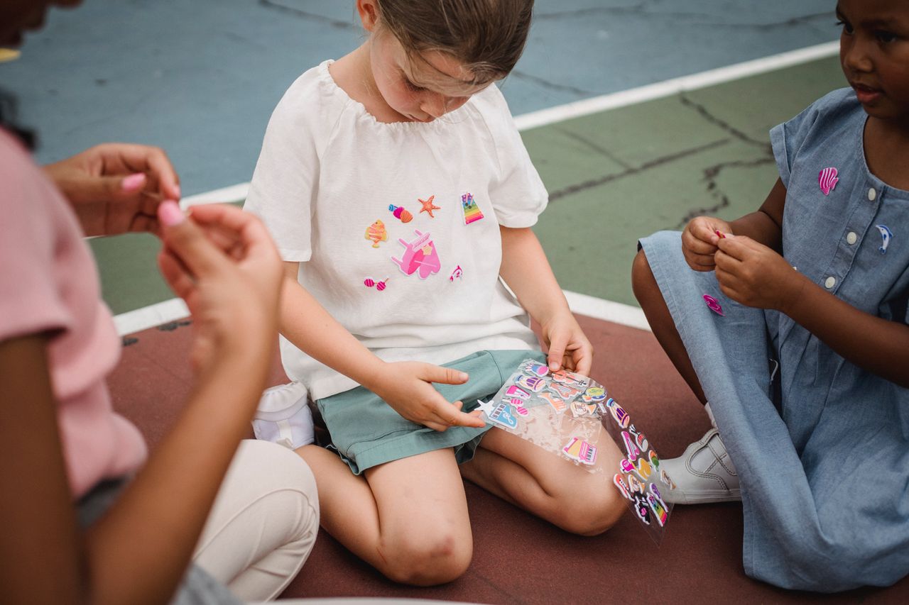 Children playing with colorful stickers on an outdoor playground. Fun and imaginative activity among friends.